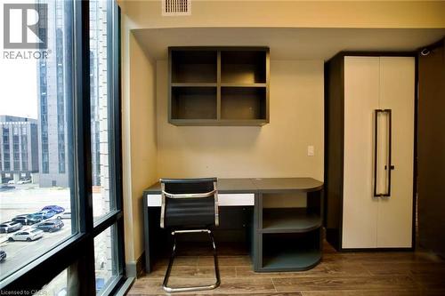 Integrated workspace featuring a built-in desk with shelving, an overhead storage unit, and wood-finish flooring - 330 Phillip Street Unit# S605, Waterloo, ON - Indoor