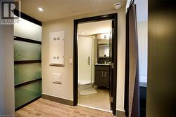 Contemporary bathroom featuring a dark wood-finish vanity with a dark countertop, a framed mirror, and a glass-enclosed shower - 
