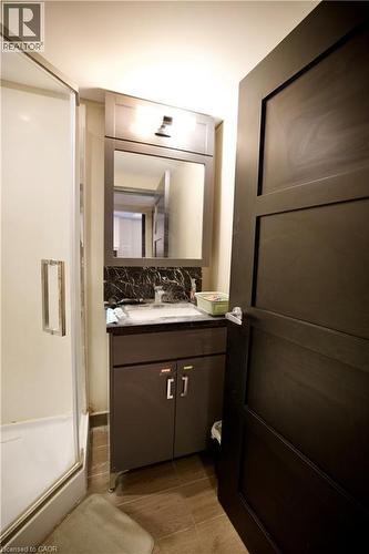 Bathroom featuring a modern vanity with a dark countertop and backsplash, a rectangular sink, and a framed mirror - 330 Phillip Street Unit# S605, Waterloo, ON - Indoor Photo Showing Bathroom