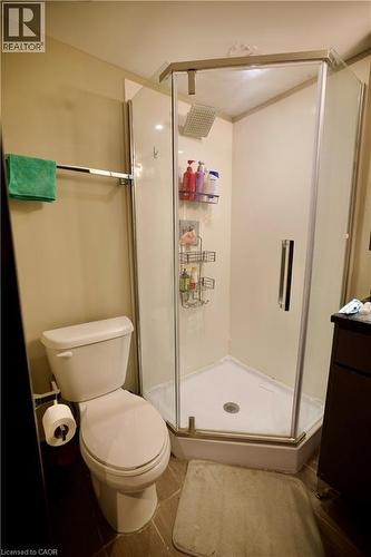 Corner glass-enclosed shower with a rainfall showerhead, white shower base, and integrated shelving - 330 Phillip Street Unit# S605, Waterloo, ON - Indoor Photo Showing Bathroom