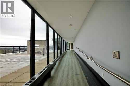 Rooftop access corridor featuring full-height windows, wood-finish flooring, recessed ceiling lights, and a continuous handrail - 330 Phillip Street Unit# S605, Waterloo, ON - Indoor Photo Showing Other Room