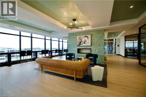 Spacious common area featuring full-height windows, light wood-finish flooring, and a stone-clad accent wall with a built-in linear fireplace - 330 Phillip Street Unit# S605, Waterloo, ON - Indoor