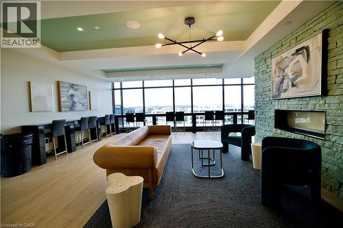 Expansive common area featuring floor-to-ceiling windows, a built-in fireplace with stacked stone surround, and wood-finish flooring - 330 Phillip Street Unit# S605, Waterloo, ON - Indoor