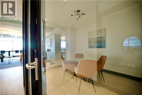 Glass-enclosed room featuring wood-finish flooring, a contemporary chandelier, and a wall-mounted art piece - 330 Phillip Street Unit# S605, Waterloo, ON - Indoor Photo Showing Dining Room
