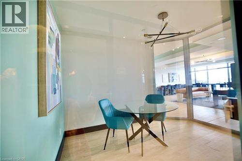 Compact dining area featuring light-toned flooring, a multi-arm chandelier, and a full-height glass partition - 330 Phillip Street Unit# S605, Waterloo, ON - Indoor Photo Showing Dining Room