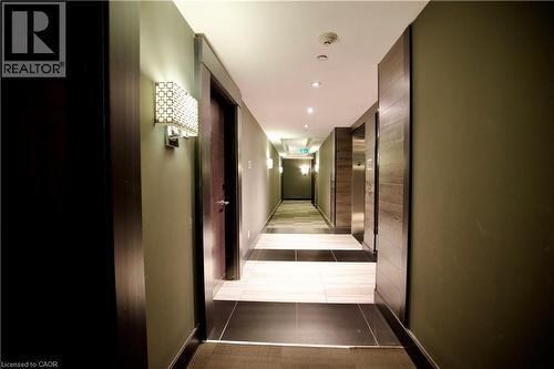 Hallway featuring contemporary wall sconces, recessed ceiling lighting, a checkerboard tile floor, dark wood-finish door frames, and stainless steel elevator doors - 330 Phillip Street Unit# S605, Waterloo, ON - Indoor Photo Showing Other Room