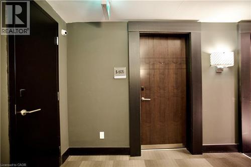 Solid wood-finish entry door with horizontal detailing, framed by dark trim - 330 Phillip Street Unit# S605, Waterloo, ON - Indoor Photo Showing Other Room
