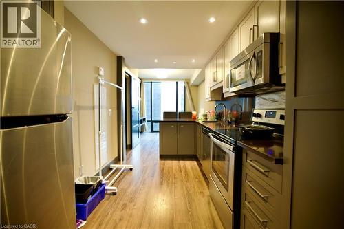 Galley kitchen featuring wood-finish flooring, recessed lighting, and stainless steel appliances - 330 Phillip Street Unit# S605, Waterloo, ON - Indoor Photo Showing Kitchen With Stainless Steel Kitchen
