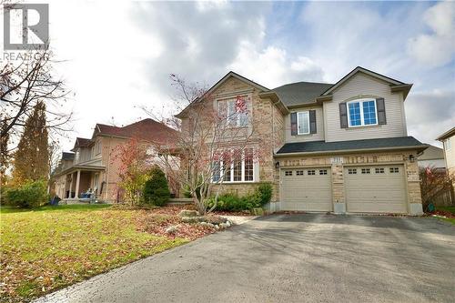 Two-story brick and siding residence featuring a two-car garage with individual doors, a paved driveway, and mature landscaping - 711 Cedar Bend Drive, Waterloo, ON - Outdoor With Facade