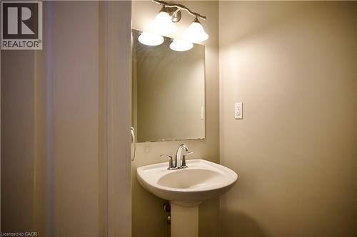 Pedestal sink with chrome faucet, illuminated by a three-light vanity fixture - 711 Cedar Bend Drive, Waterloo, ON - Indoor Photo Showing Bathroom
