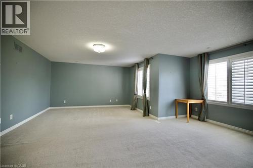 Spacious room featuring light gray carpeting, neutral-toned walls, and multiple windows with white plantation shutters - 711 Cedar Bend Drive, Waterloo, ON - Indoor Photo Showing Other Room