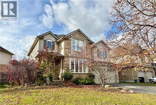 Two-story residence featuring a brick facade with stone accents, a dual-door garage, multiple gabled rooflines, and mature landscaping - 711 Cedar Bend Drive, Waterloo, ON - Outdoor With Facade