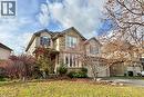 Two-story residence featuring a brick facade with stone accents, a dual-door garage, multiple gabled rooflines, and mature landscaping - 711 Cedar Bend Drive, Waterloo, ON  - Outdoor With Facade 