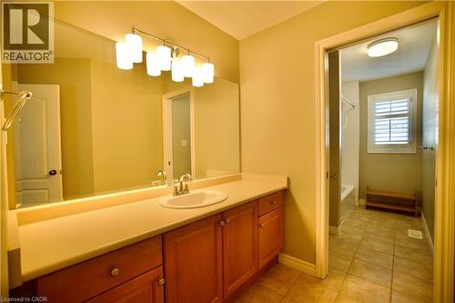 Bathroom featuring a vanity with wood-finish cabinetry, a single basin sink, and a large wall-mounted mirror - 711 Cedar Bend Drive, Waterloo, ON - Indoor Photo Showing Bathroom