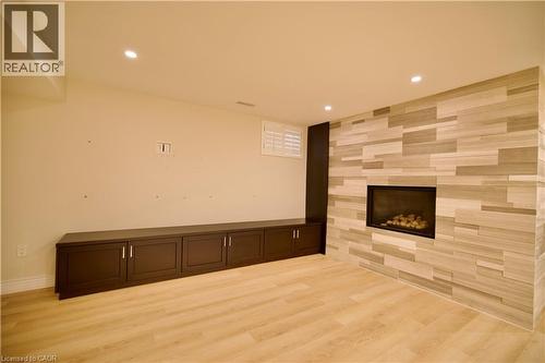 Modern linear fireplace with a textured stone surround and a dark wood-finish built-in storage unit - 711 Cedar Bend Drive, Waterloo, ON - Indoor With Fireplace