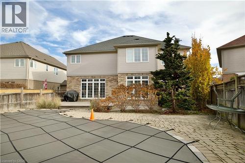 Rear exterior featuring a covered pool, paver patio, mature landscaping, and a multi-level deck with direct access to the interior - 711 Cedar Bend Drive, Waterloo, ON - Outdoor