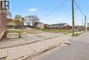 Expansive urban lot featuring a mix of concrete and grass areas, bordered by a brick building and a public sidewalk - 868 King Street E, Cambridge, ON 