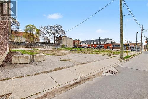 Expansive urban lot featuring a mix of concrete and grass areas, bordered by a brick building and a public sidewalk - 868 King Street E, Cambridge, ON 