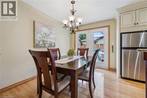 Dining area featuring wood-finish flooring, a contemporary chandelier, light-toned walls, and a pair of French doors providing outdoor access - 574 Sprucehill Avenue, Waterloo, ON - Indoor Photo Showing Dining Room