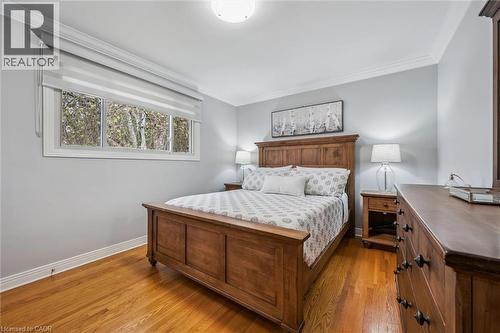 Spacious bedroom featuring wood-finish flooring, crown molding, a large window, and light-toned wall paint - 574 Sprucehill Avenue, Waterloo, ON - Indoor Photo Showing Bedroom