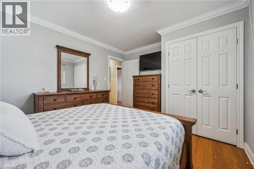 Bedroom featuring light gray walls, white crown molding, wood-finish flooring, and a double-door closet with paneled doors - 574 Sprucehill Avenue, Waterloo, ON - Indoor Photo Showing Bedroom