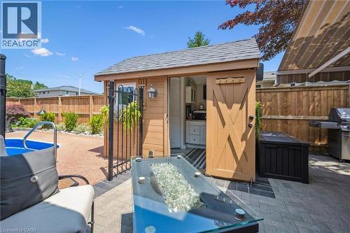 Wood-sided outdoor structure with barn-style sliding door, interior cabinetry, and an exterior wall lantern - 574 Sprucehill Avenue, Waterloo, ON - Outdoor