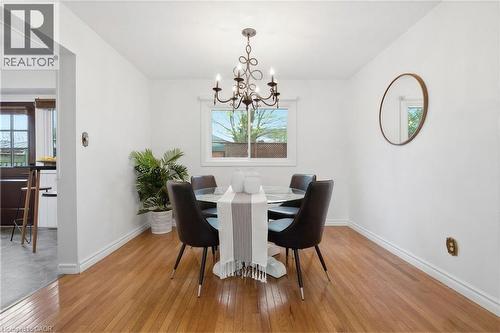 Bright dining area featuring wood-finish flooring, and a classic chandelier light fixture - 56 Angela Crescent, Cambridge, ON - Indoor Photo Showing Dining Room