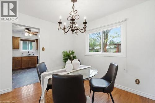 Dining area featuring a decorative chandelier, hardwood flooring, and a large window - 56 Angela Crescent, Cambridge, ON - Indoor Photo Showing Dining Room