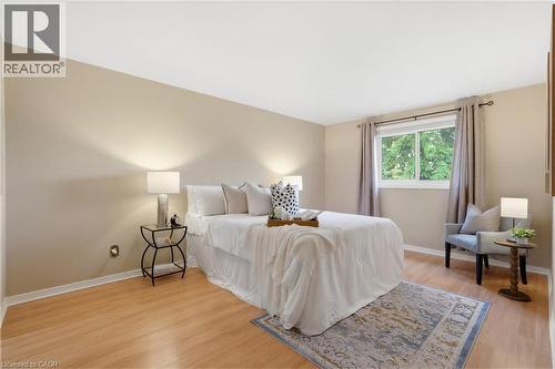 Primary bedroom featuring wood-finish flooring, a neutral color palette, and a large window - 56 Angela Crescent, Cambridge, ON - Indoor Photo Showing Bedroom