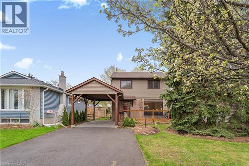 Two-story residence with a covered carport, expansive driveway, and a front deck featuring wooden railing - 56 Angela Crescent, Cambridge, ON - Outdoor With Facade