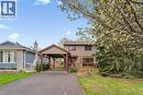 Two-story residence with a covered carport, expansive driveway, and a front deck featuring wooden railing - 56 Angela Crescent, Cambridge, ON  - Outdoor With Facade 