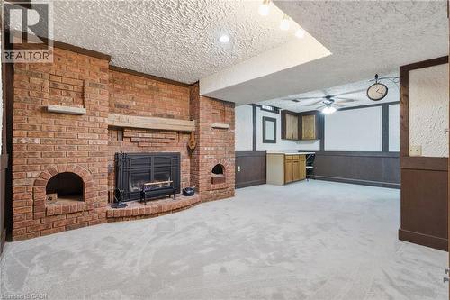 Spacious interior featuring a large brick fireplace, light-toned carpeting, and dark wainscoting - 56 Angela Crescent, Cambridge, ON - Indoor With Fireplace