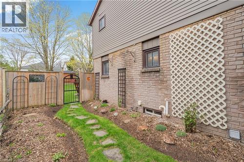 Side yard featuring a stepping stone pathway, wood privacy fence with decorative metal accents, and a wrought iron gate - 56 Angela Crescent, Cambridge, ON - Outdoor