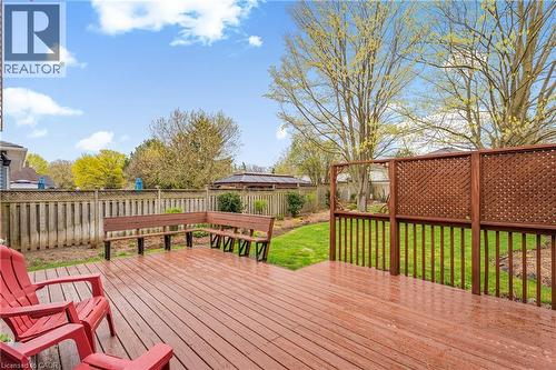 Spacious wood-finish deck with built-in bench seating, lattice privacy screens, and a baluster railing overlooking a fenced backyard with mature trees and a manicured lawn - 56 Angela Crescent, Cambridge, ON - Outdoor With Deck Patio Veranda