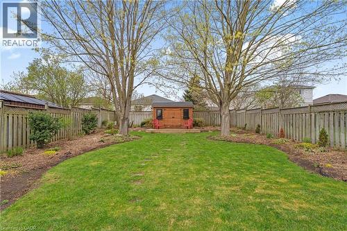 Expansive backyard featuring a manicured lawn, two mature trees, a wooden shed, a raised deck area, and perimeter fencing - 56 Angela Crescent, Cambridge, ON - Outdoor With Backyard