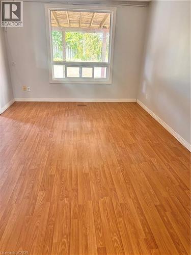 Spacious interior room featuring wood-finish flooring, a large window, and light-toned wall finishes - 206 Northmanor Crescent, Kitchener, ON 