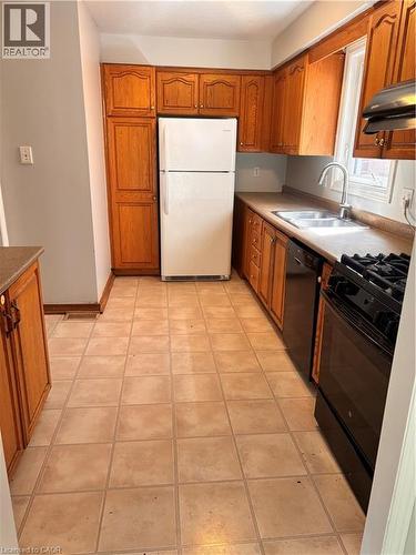 Kitchen featuring extensive wood cabinetry, tile flooring, and a stainless steel sink with a high-arc faucet - 206 Northmanor Crescent, Kitchener, ON 