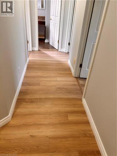Hallway featuring wood-finish flooring, light gray walls, and white baseboards - 206 Northmanor Crescent, Kitchener, ON 