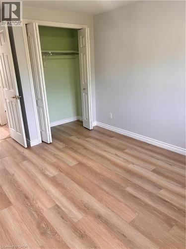 Interior room featuring wood-finish flooring, light grey walls, white baseboards, and a bi-fold closet with a hanging rod - 206 Northmanor Crescent, Kitchener, ON 