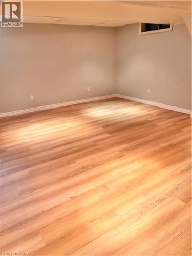 Spacious room featuring wood-finish flooring, light grey painted walls, white baseboards, and a window opening - 206 Northmanor Crescent, Kitchener, ON 