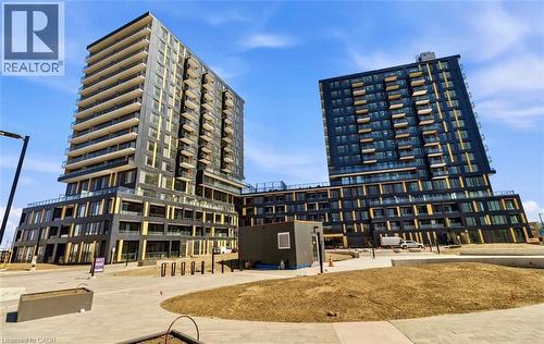 Contemporary urban development featuring two multi-story buildings with dark facades and multiple balconies - 4878 Powers Common Unit# 301, Burlington, ON - Outdoor With Balcony With Facade