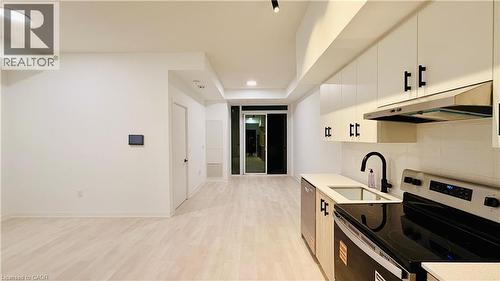 Open-concept living area with light wood-finish flooring, recessed lighting, and a contemporary kitchen - 4878 Powers Common Unit# 301, Burlington, ON - Indoor Photo Showing Kitchen