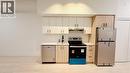 Modern kitchen featuring white upper cabinetry and light wood-finish lower cabinetry, stainless steel appliances, a white subway tile backsplash, and light wood-finish flooring - 4878 Powers Common Unit# 301, Burlington, ON  - Indoor Photo Showing Kitchen 