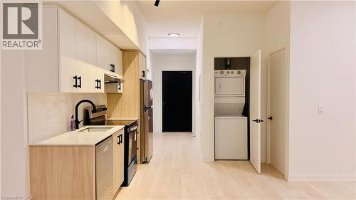 Modern kitchen featuring two-tone cabinetry with black hardware, light-toned countertops, and a subway tile backsplash - 4878 Powers Common Unit# 301, Burlington, ON - Indoor