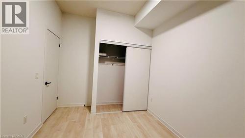 Room featuring light wood-finish flooring, white walls, and a built-in closet with sliding doors - 4878 Powers Common Unit# 301, Burlington, ON - Indoor Photo Showing Other Room