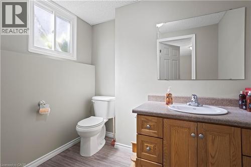 Bathroom featuring a wood-finish vanity with a countertop, an undermount sink, and a large wall-mounted mirror - 179 Vancouver Street, London, ON - Indoor Photo Showing Bathroom