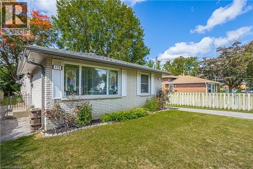 Light-colored brick exterior featuring white shutters and a paved driveway leading to a white picket fence - 179 Vancouver Street, London, ON - Outdoor