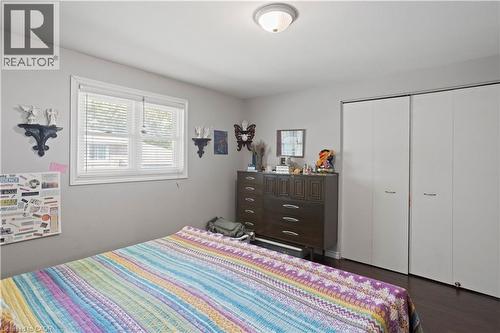 Neutral wall color with a window featuring blinds, dark wood-finish flooring, and bi-fold closet doors - 179 Vancouver Street, London, ON - Indoor Photo Showing Bedroom