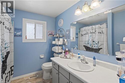 Full bathroom featuring a single vanity, a large wall-mounted mirror, overhead lighting, a toilet, and a window with privacy glass - 179 Vancouver Street, London, ON - Indoor Photo Showing Bathroom
