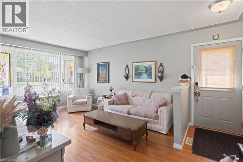 Living space featuring wood-finish flooring, a large picture window with vertical blinds, and light gray wall paint - 179 Vancouver Street, London, ON - Indoor Photo Showing Living Room